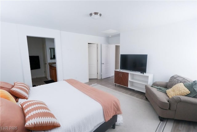bedroom featuring light wood-style flooring and ensuite bathroom