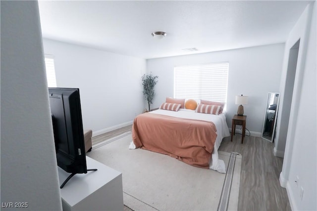 bedroom featuring light wood finished floors, multiple windows, visible vents, and baseboards