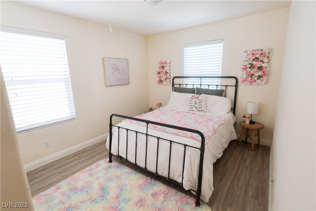 bedroom with multiple windows, wood finished floors, and baseboards
