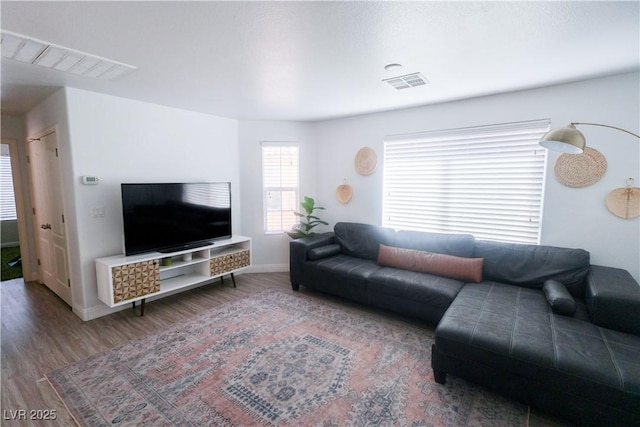 living room featuring wood finished floors, baseboards, and visible vents