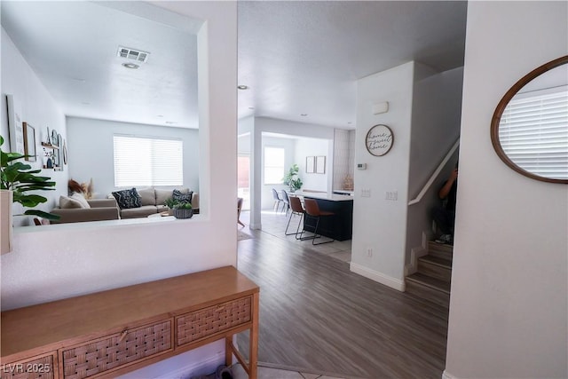 corridor featuring stairs, visible vents, wood finished floors, and baseboards