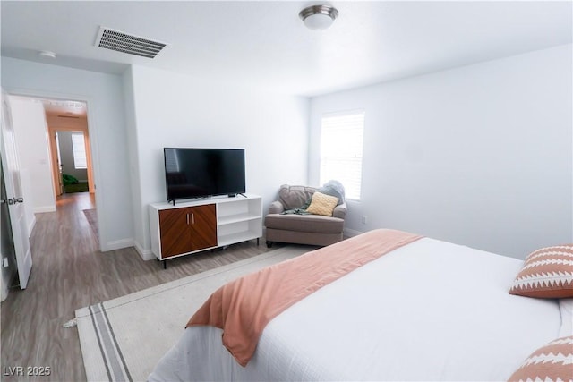 bedroom featuring baseboards, light wood-style flooring, visible vents, and multiple windows