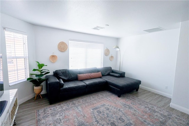 living area with wood finished floors, a healthy amount of sunlight, and visible vents