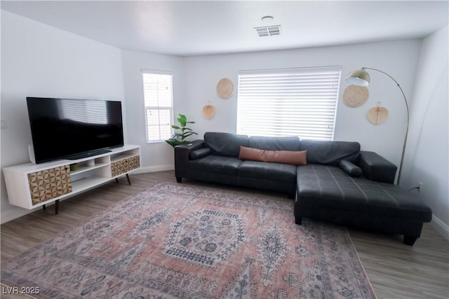 living room featuring baseboards, visible vents, and wood finished floors