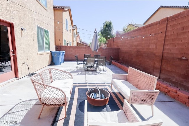 view of patio featuring outdoor dining area, a fenced backyard, and an outdoor living space with a fire pit