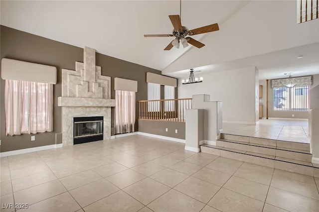 unfurnished living room featuring tile patterned flooring, a large fireplace, baseboards, and ceiling fan with notable chandelier