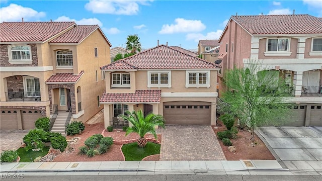 mediterranean / spanish-style house featuring driveway, a tile roof, an attached garage, and stucco siding