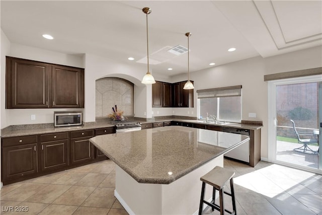 kitchen featuring a kitchen island, appliances with stainless steel finishes, dark brown cabinets, and recessed lighting