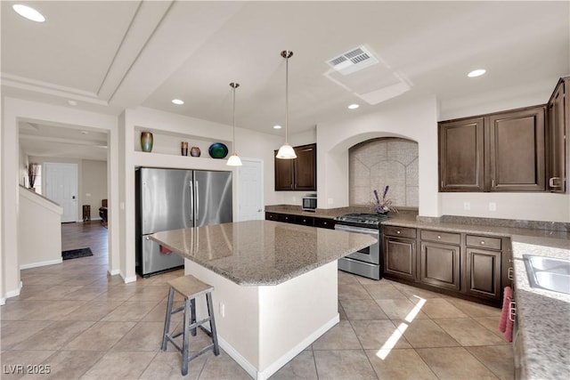 kitchen featuring light stone counters, a center island, stainless steel appliances, visible vents, and dark brown cabinets