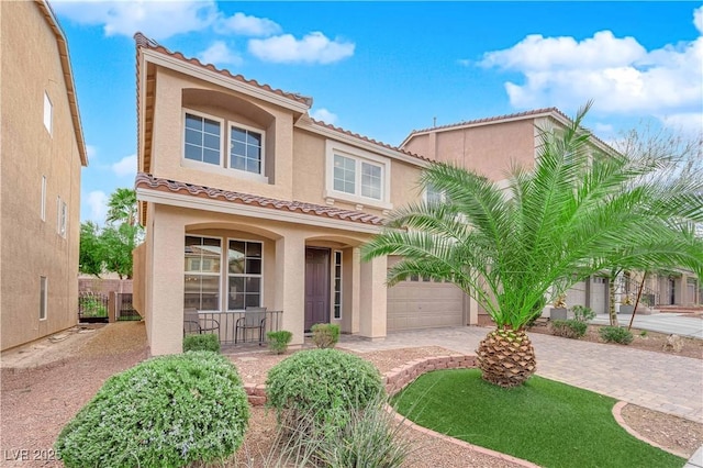 mediterranean / spanish-style home with driveway, a garage, a tiled roof, covered porch, and stucco siding