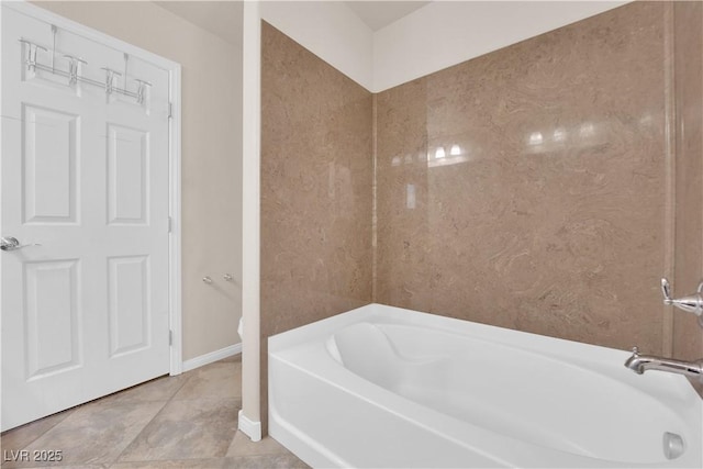 bathroom featuring a tub to relax in, tile patterned flooring, and baseboards