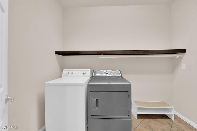 laundry room featuring laundry area, washing machine and dryer, baseboards, and light tile patterned flooring