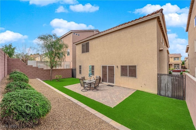 back of house featuring a lawn, a patio area, a fenced backyard, and stucco siding