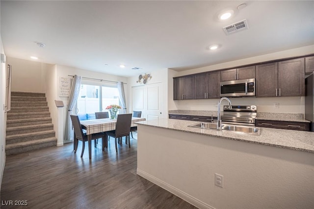 kitchen with dark brown cabinetry, visible vents, stainless steel microwave, and a sink