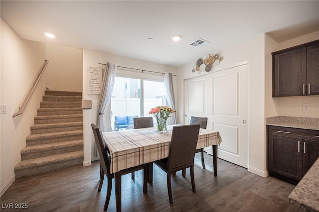 dining room featuring dark wood-style flooring, visible vents, stairway, and baseboards