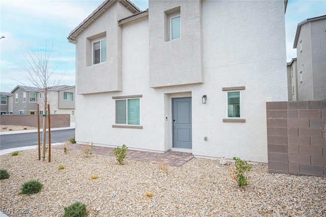 view of front facade with fence and stucco siding