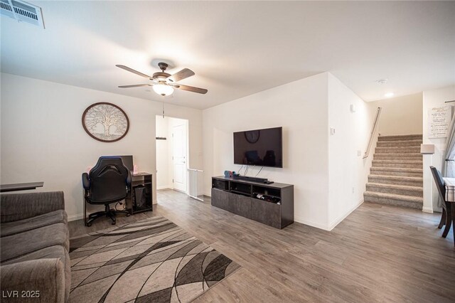 living room with visible vents, stairway, a ceiling fan, wood finished floors, and baseboards