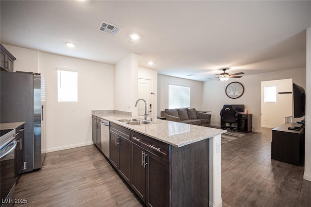 kitchen featuring stainless steel appliances, visible vents, a sink, dark brown cabinets, and a peninsula