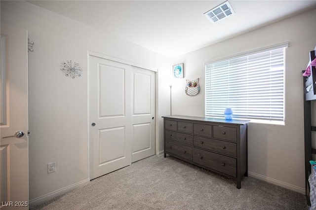 bedroom featuring baseboards, visible vents, a closet, and light colored carpet