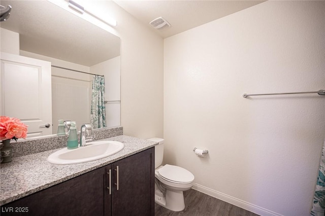 bathroom with toilet, wood finished floors, vanity, visible vents, and baseboards