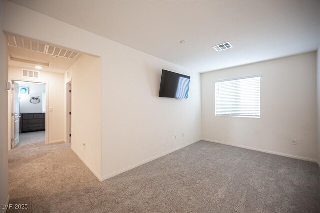 empty room with carpet floors, visible vents, and baseboards