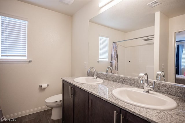 bathroom with toilet, wood finished floors, a sink, and visible vents