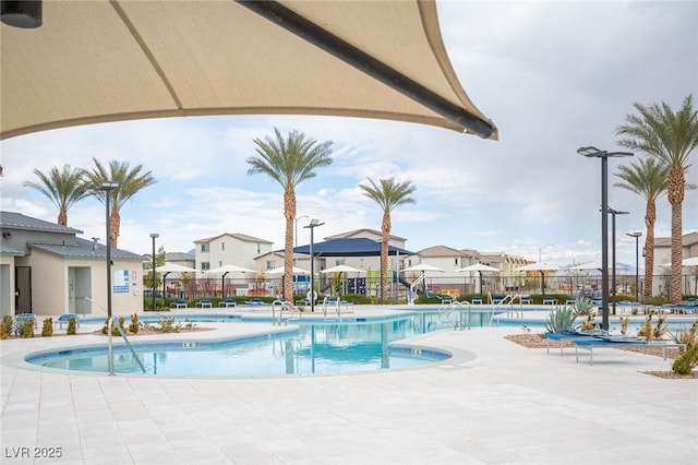 community pool with a residential view, a patio area, and fence