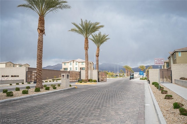 view of street featuring street lighting, a gate, sidewalks, a gated entry, and curbs