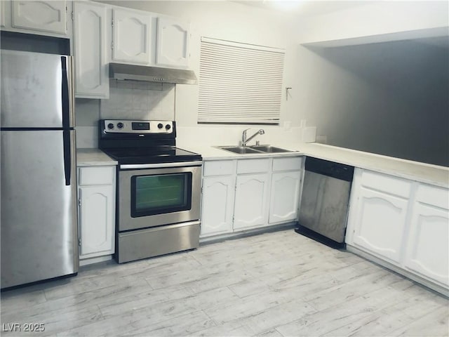 kitchen featuring white cabinets, appliances with stainless steel finishes, light countertops, under cabinet range hood, and a sink