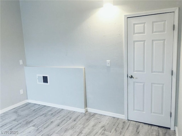 unfurnished room with light wood-type flooring, visible vents, and baseboards