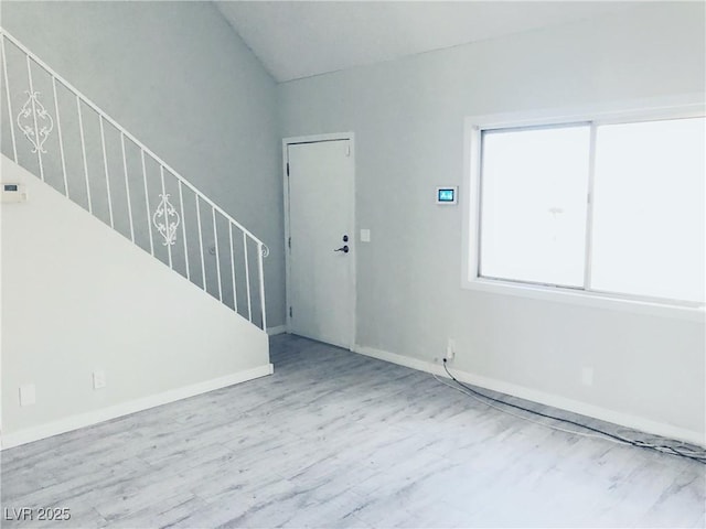 empty room featuring stairs, baseboards, and wood finished floors