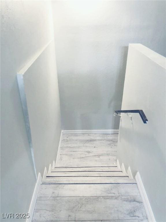 stairs featuring wood finished floors and baseboards