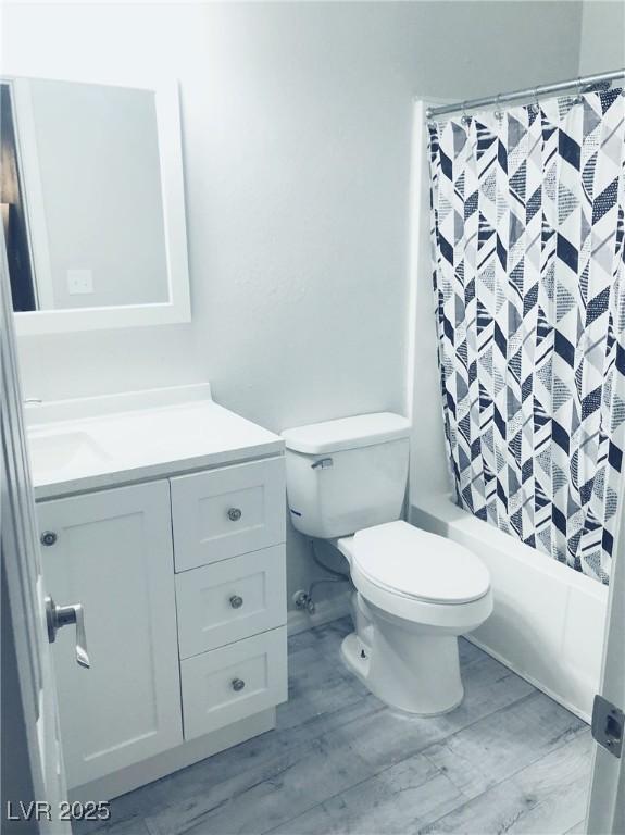 bathroom featuring vanity, shower / bath combination with curtain, wood finished floors, and toilet