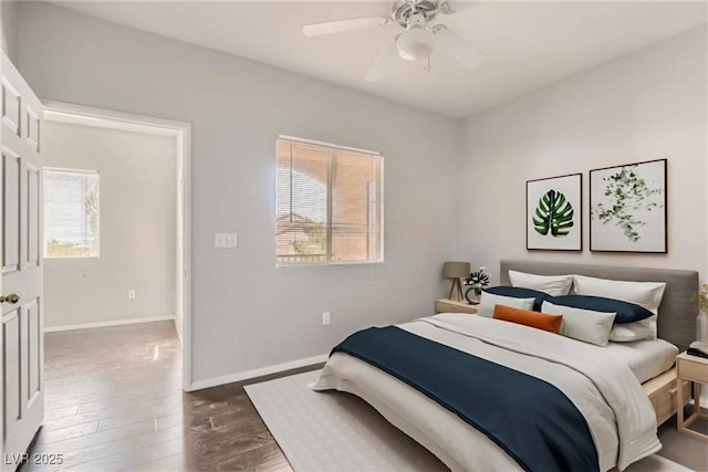 bedroom featuring dark wood-style floors, multiple windows, a ceiling fan, and baseboards