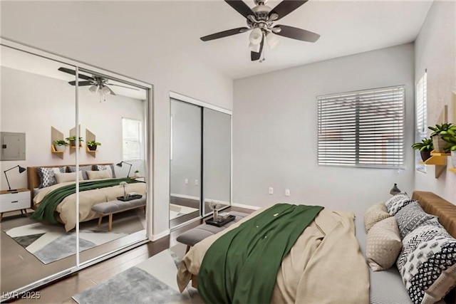 bedroom featuring electric panel, ceiling fan, baseboards, and wood finished floors