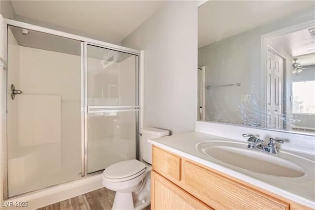 bathroom featuring vanity, wood finished floors, a shower stall, and toilet