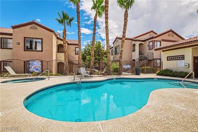 community pool featuring a hot tub, fence, and a patio