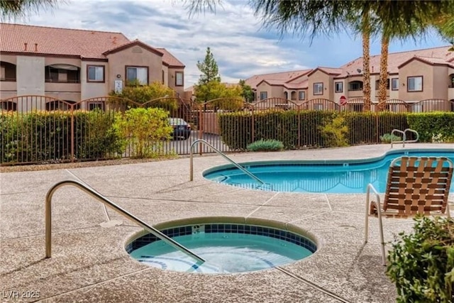 pool with fence, a residential view, and a hot tub