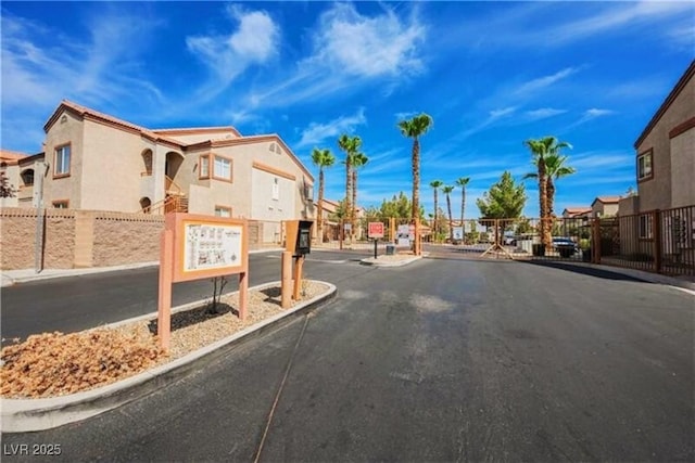 view of street with a residential view, sidewalks, curbs, and a gated entry