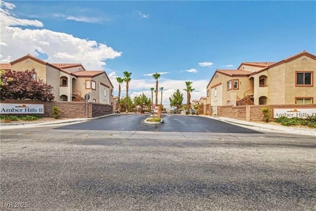 view of road with sidewalks, a residential view, a gated entry, and curbs