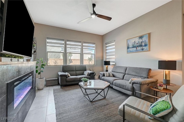 living area with light tile patterned floors, ceiling fan, and a glass covered fireplace