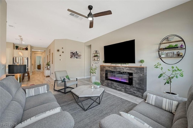 living room with a ceiling fan, baseboards, visible vents, and a tiled fireplace