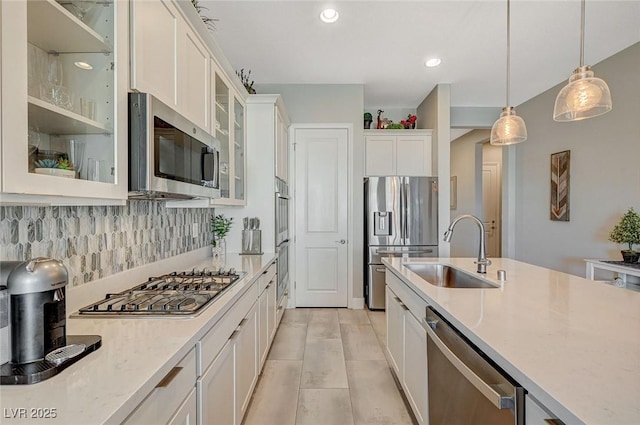 kitchen featuring pendant lighting, stainless steel appliances, decorative backsplash, white cabinetry, and a sink