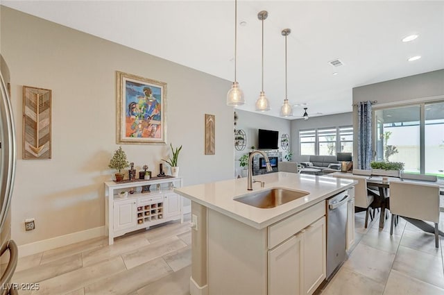 kitchen featuring light countertops, hanging light fixtures, open floor plan, a sink, and dishwasher