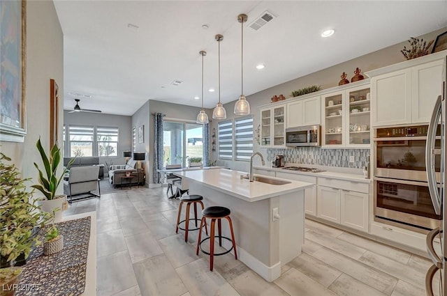 kitchen featuring stainless steel appliances, visible vents, backsplash, white cabinetry, and a sink