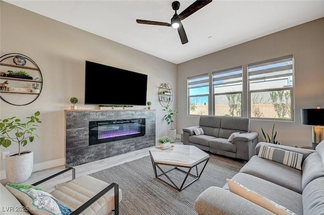 living room featuring a fireplace, baseboards, and ceiling fan