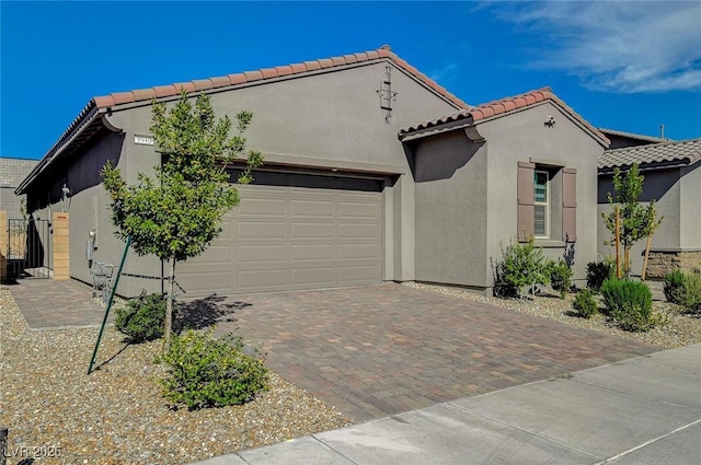 view of side of home with a tiled roof, decorative driveway, an attached garage, and stucco siding