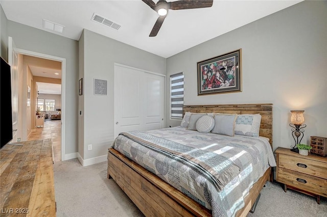 bedroom featuring baseboards, visible vents, a ceiling fan, light colored carpet, and a closet