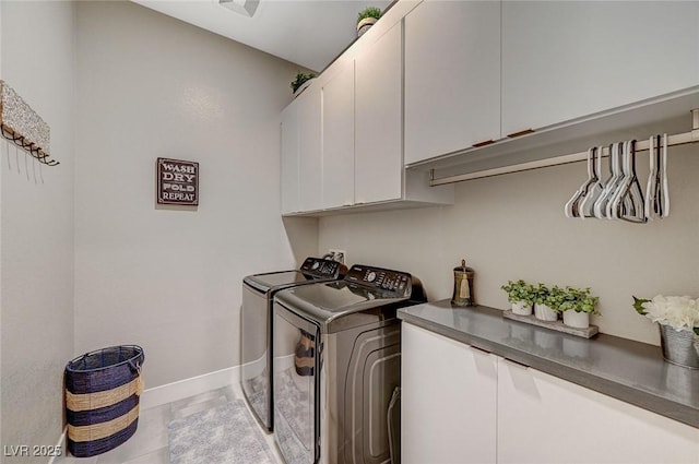 laundry room with tile patterned flooring, washing machine and dryer, cabinet space, and baseboards