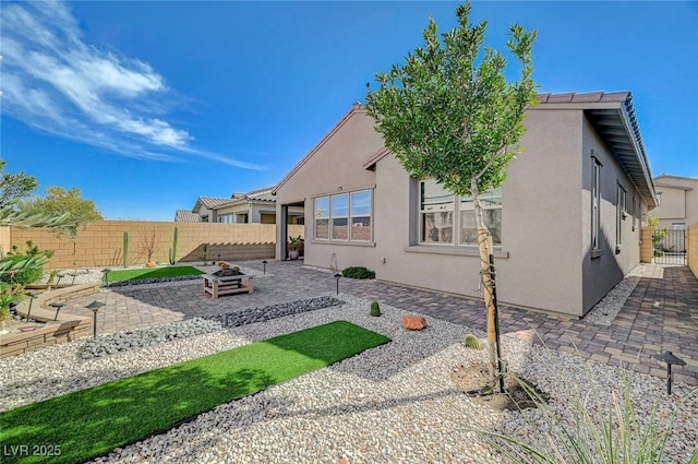 rear view of property featuring fence private yard, stucco siding, and a patio